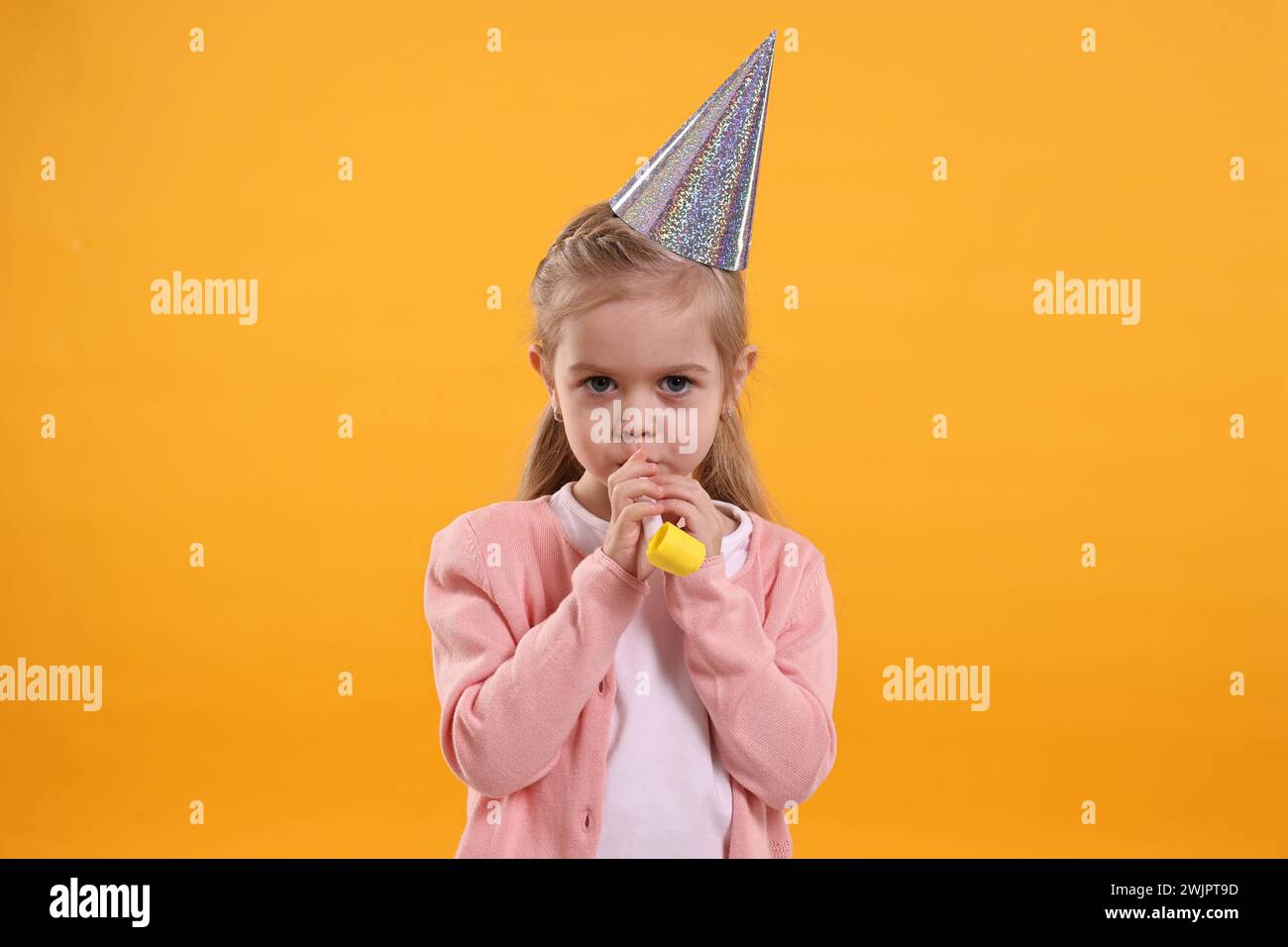 Birthday celebration. Cute little girl in party hat with blower on ...