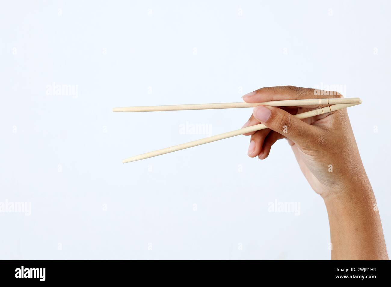 Female Hand Holding Disposable Bamboo Chopstick on White Background Stock Photo