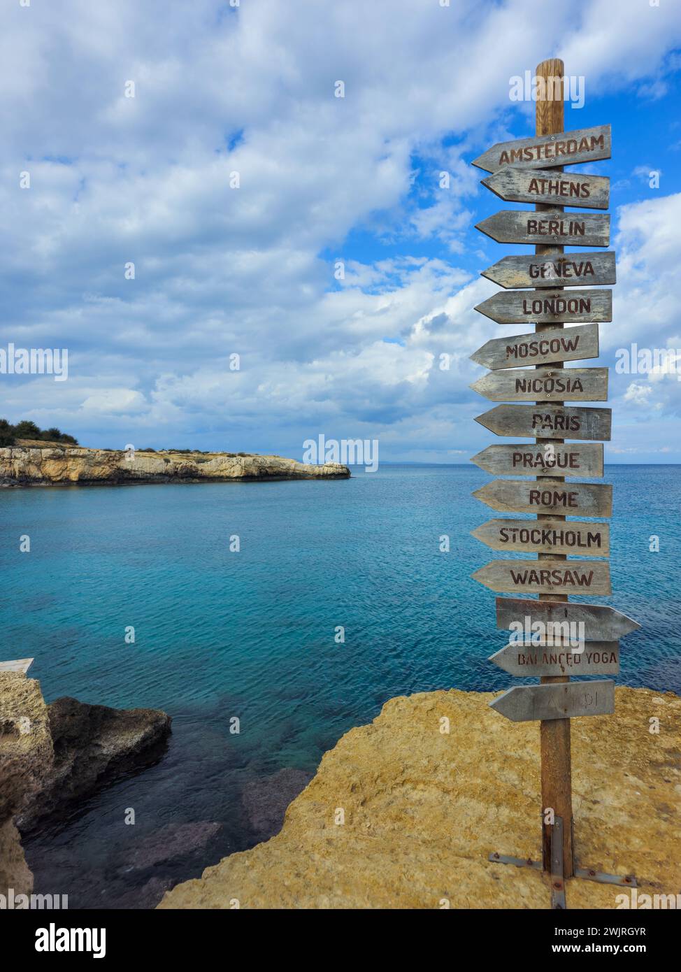 Signpost of direction of European capital cities on a wooden board in the coast against cloudy sky Stock Photo