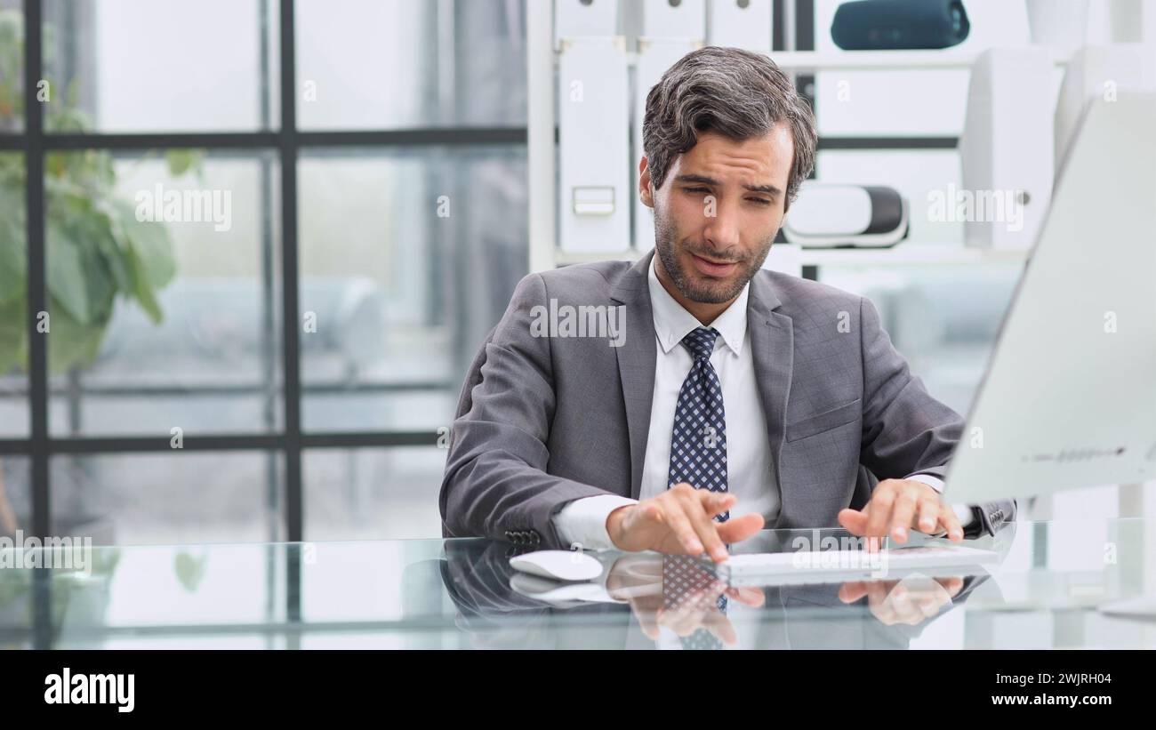 Man looking at computer monitor while sitting in modern office Stock Photo