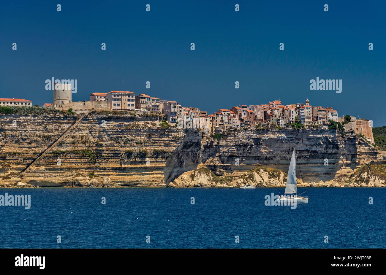 Citadelle on top of limestone cliffs, seen from the sea, King Aragon Steps on left, sailboat, Bonifacio, Corse-du-Sud, Corsica, France Stock Photo