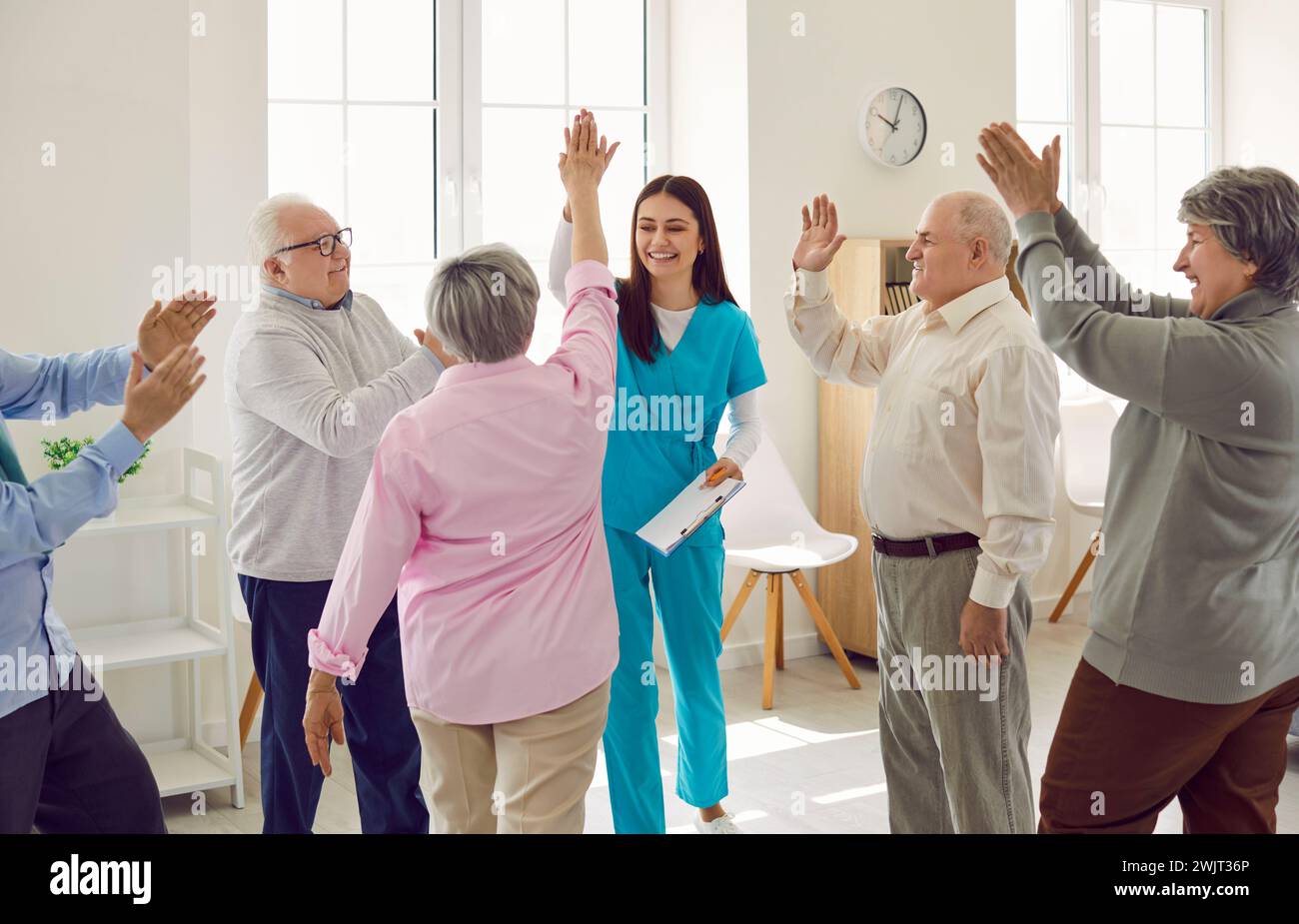 Group of happy senior people together with young nurse having fun at retirement home Stock Photo