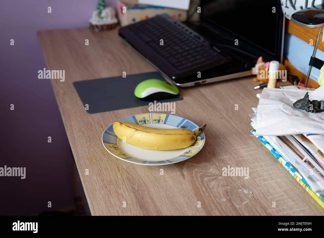 A beautiful fresh banana on a work table at home or in the office with a computer or laptop - notebook. Stock Photo