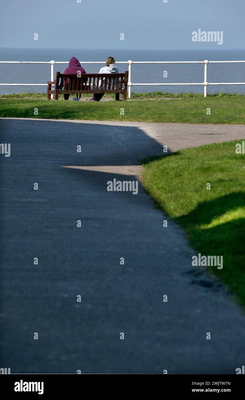 couple sitting on bench overlooking north sea southwold suffolk england Stock Photo