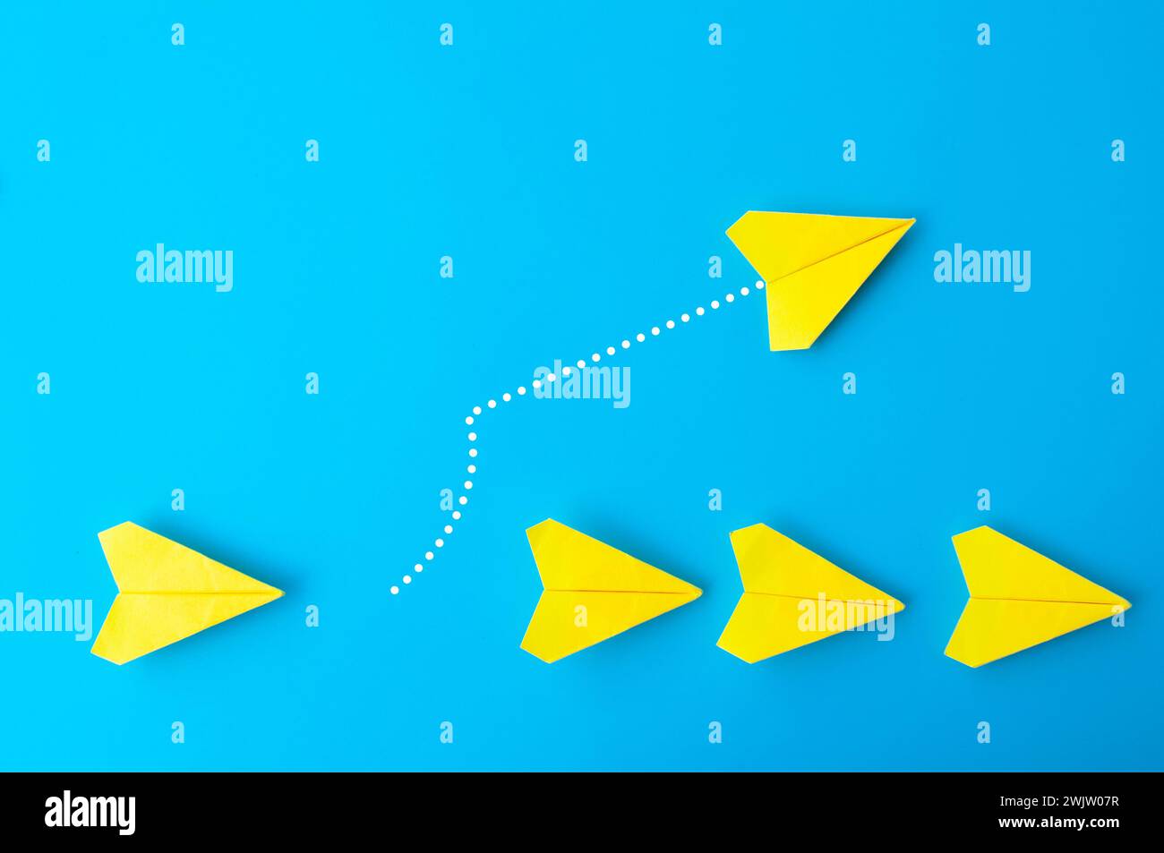 Top view of yellow paper airplanes with one flying at different direction. Stock Photo