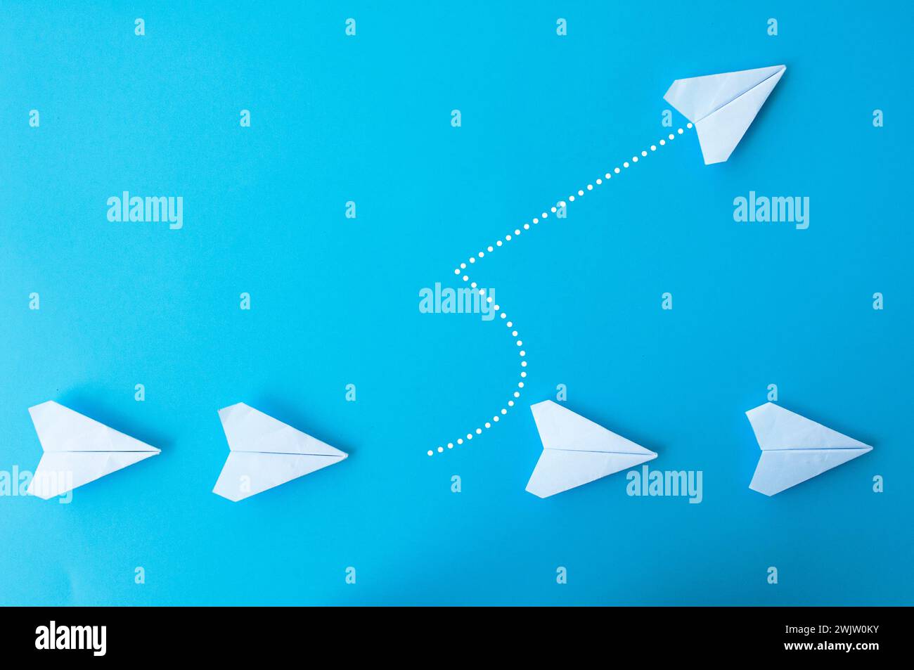 Top view of white paper airplanes origami with one flying at different direction. Stock Photo