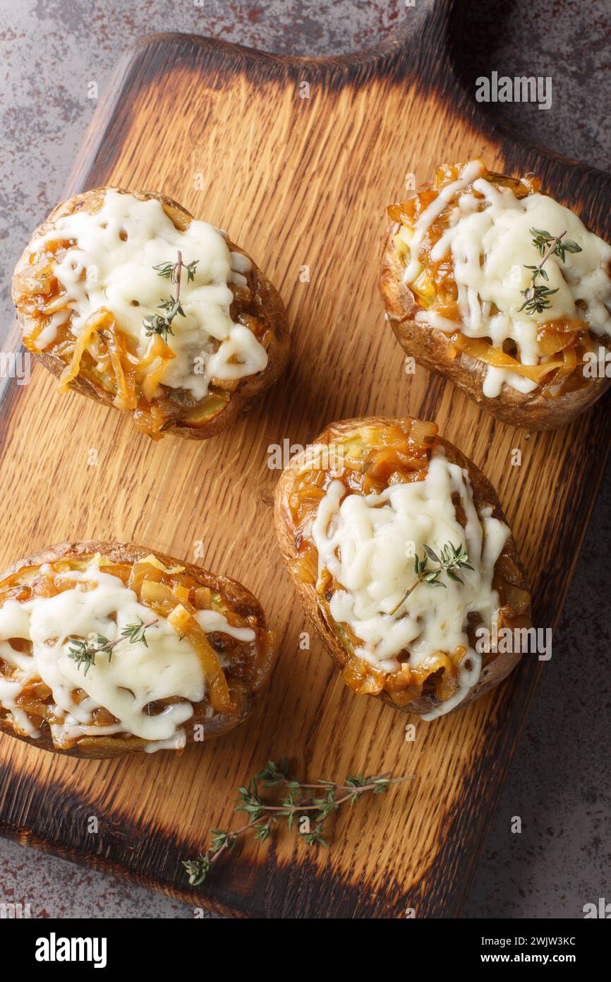 Cheesy French Onion Baked Potatoes closeup on the wooden board on the table. Vertical top view from above Stock Photo