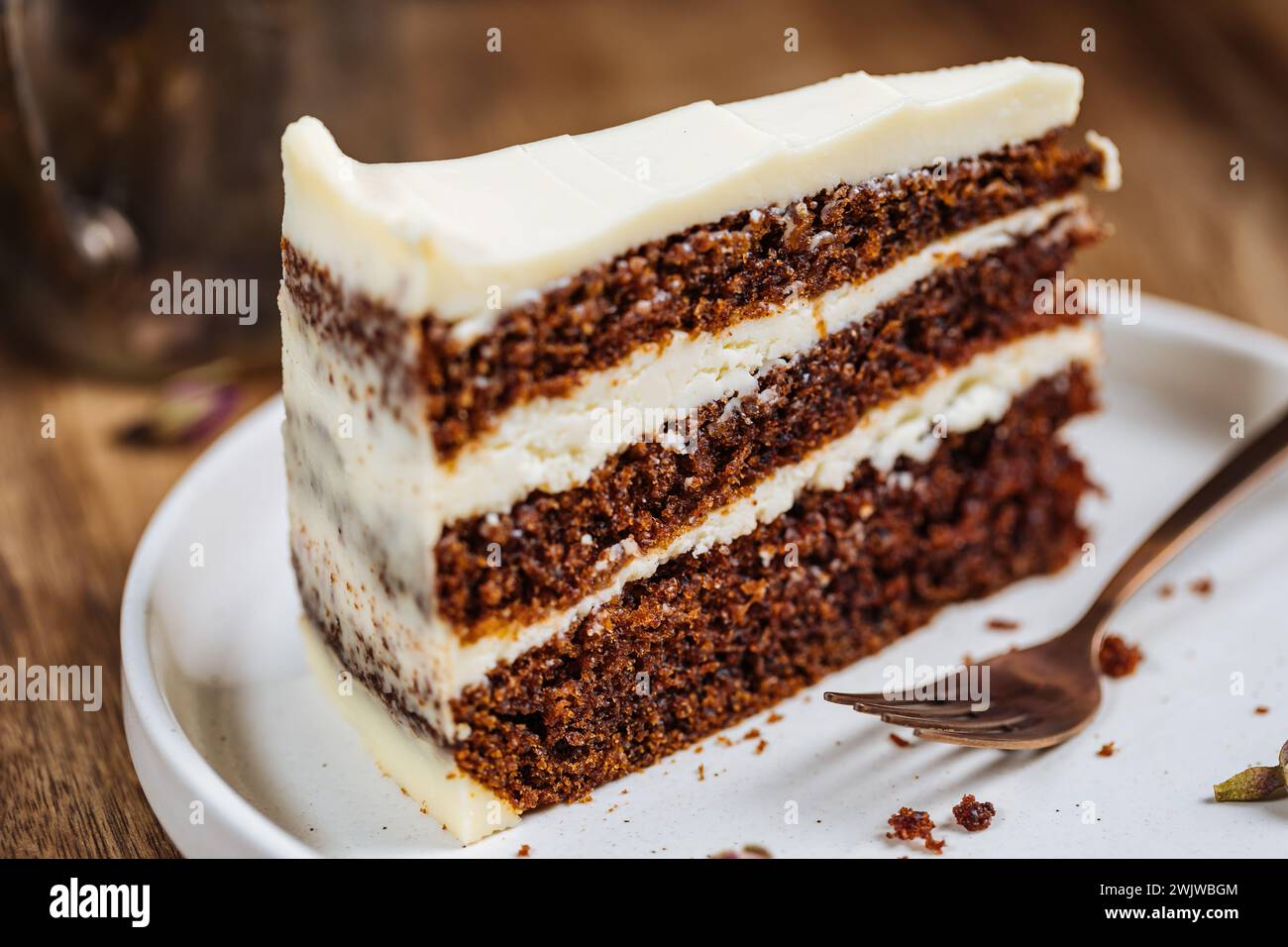 A piece of carrot cake served on rustic wooden tray. bright sunny scene. Layered cake with cream cheese frosting and fluffy biscuit. Stock Photo