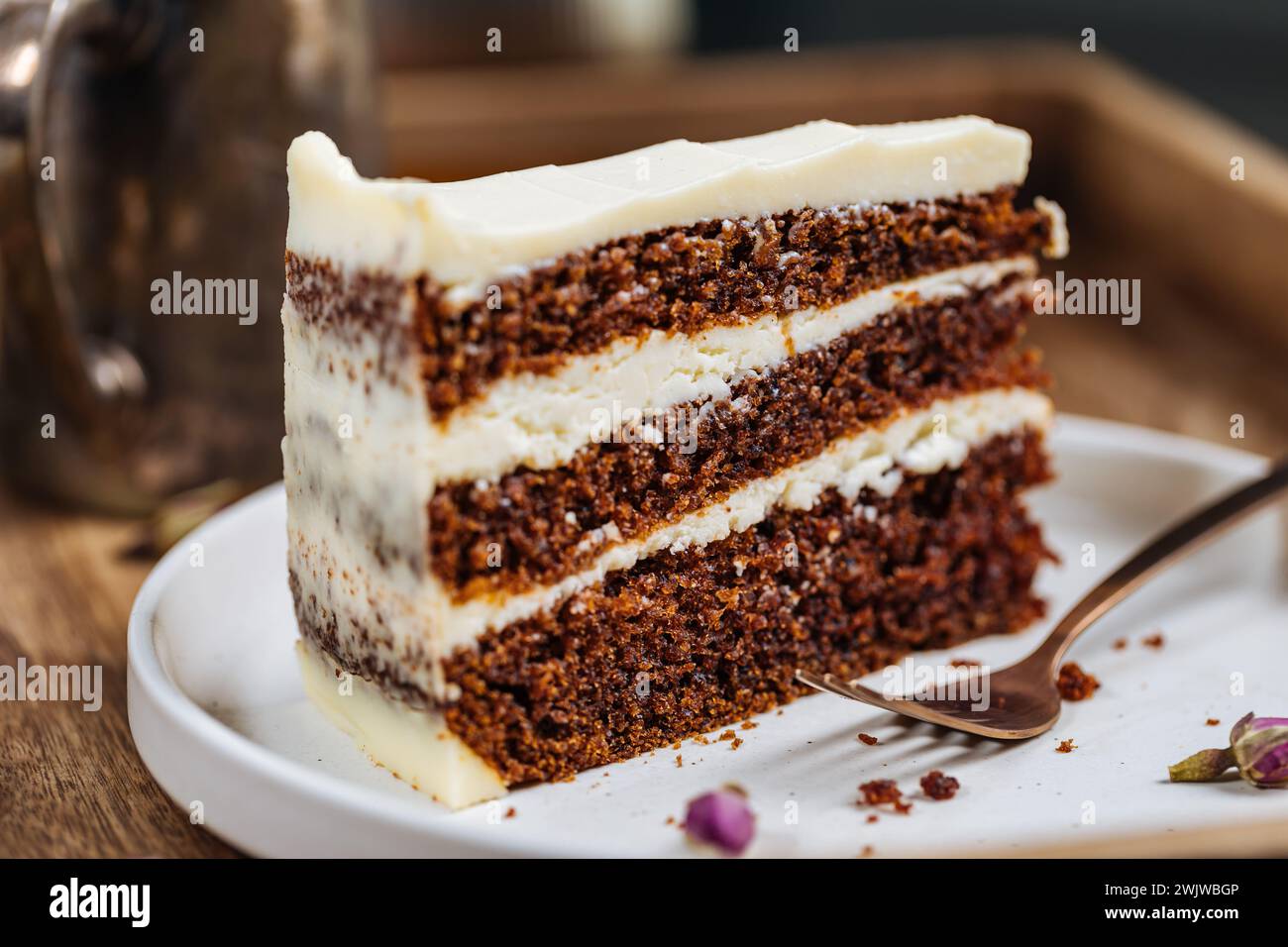 A piece of carrot cake served on rustic wooden tray. bright sunny scene. Layered cake with cream cheese frosting and fluffy biscuit. Stock Photo