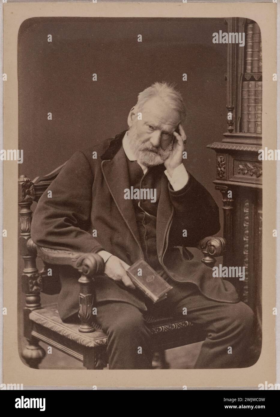 Lucien Waléry (1830-1890). Victor Hugo seated, front look, left hand supporting his head, delivers in his right hand. EPREOVE ON CIRÉRA albumin paper, 1879. PARIS, Maison de Victor Hugo. 71161-37 Leather, seated, French writer, chair, face, book, left hand, portrait, look, support, hold, head Stock Photo