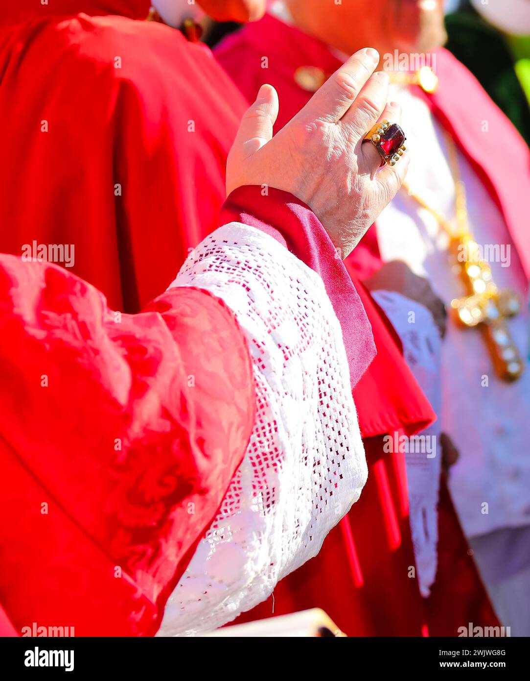 hand of the priest with red cassock during the blessing of the faithful