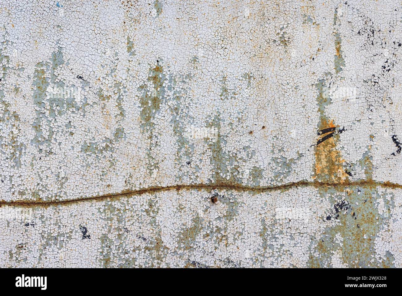 Peeling and cracked paint on an old metal sheet with a crooked rusty