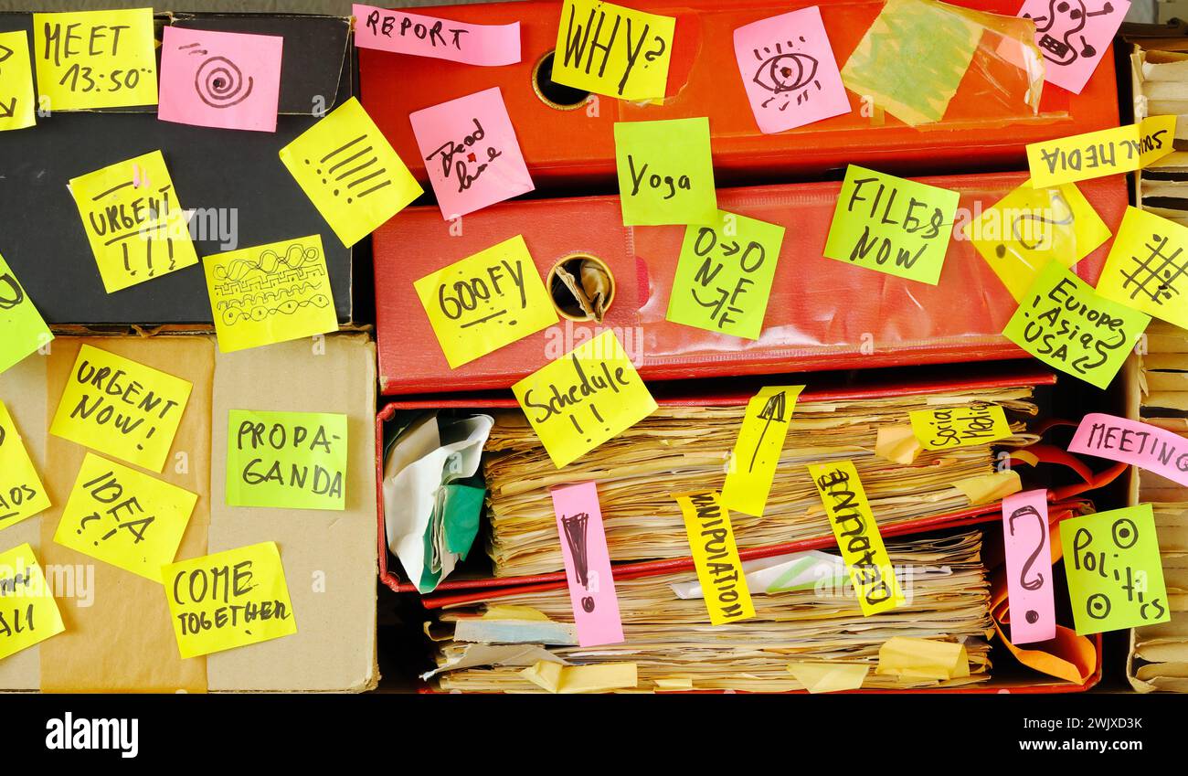 Messy file folder,sticky notes and old papers.Red tape, bureaucracy,overworked,burn out,exploitation,messy office and chaotic business concept. Stock Photo