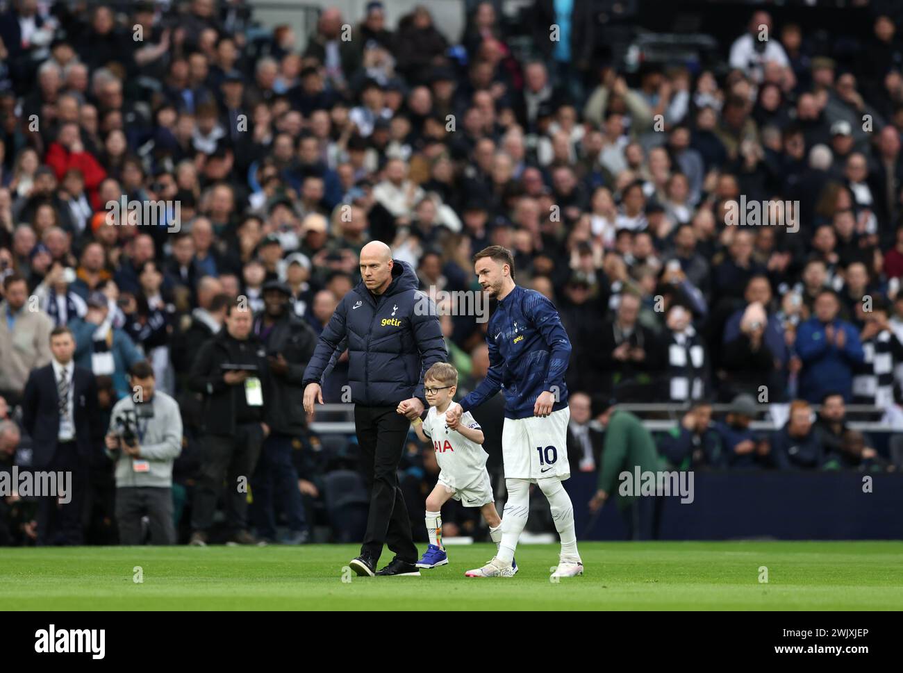 Tottenham Hotspur's James Maddison (right) walks on to the pitch with mascot Samuel (centre) ahead of the Premier League match at the Tottenham Hotspur Stadium, London. Picture date: Saturday February 17, 2024. Stock Photo