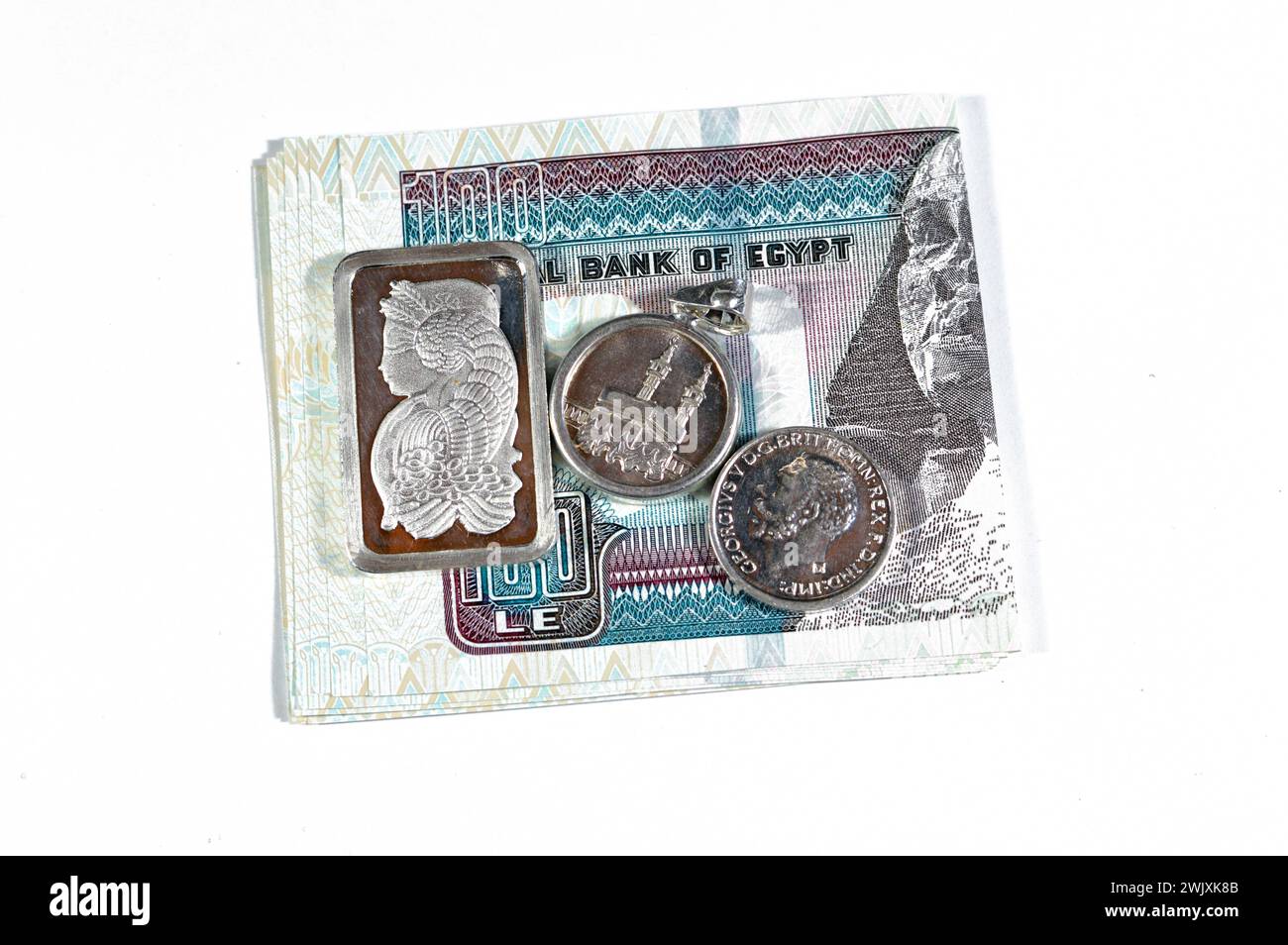 Egyptian pounds cash money with silver precious metal ounce bar of pure silver, Islamic pound features Kaaba, Masjid Haram and The sovereign, a Britis Stock Photo