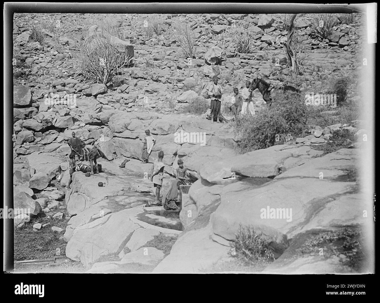 View of Africa - rocky landscape with characters on horseback on the edge of a reserve of water (username). Glass photographic plate. Museum of Romantic Life. Stock Photo