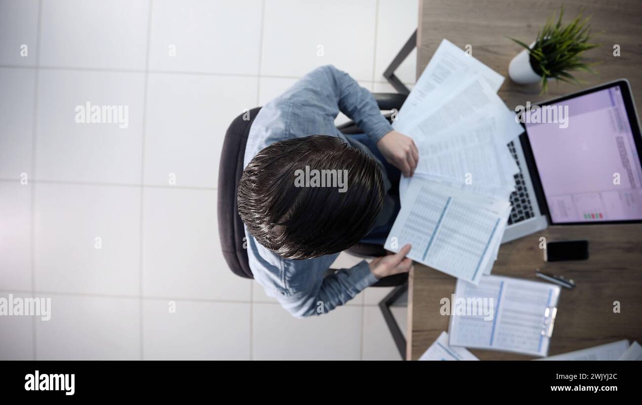 A male office worker is scattering papers Stock Photo