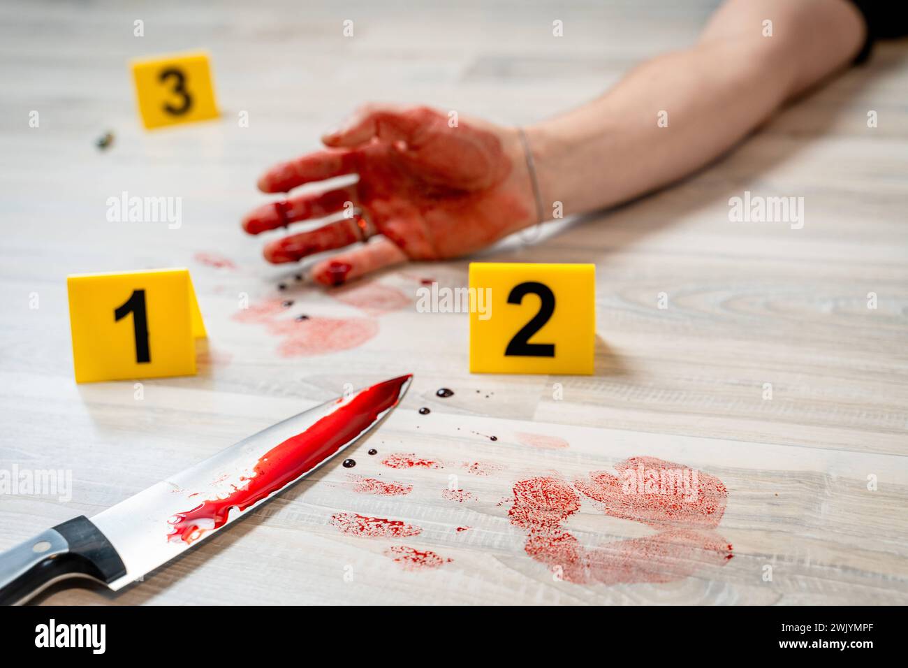 Augsburg, Bavaria, Germany - February 16, 2024: Symbolic image crime scene of a murder case staged scene. Man smeared with blood lying on the ground with police evidence markings *** Symbolbild Tatort eines Mordfalls gestellte Szene. Mit Blut verschmierter Mann liegt auf dem Boden mit Beweismittel Markierungen der Polizei Stock Photo