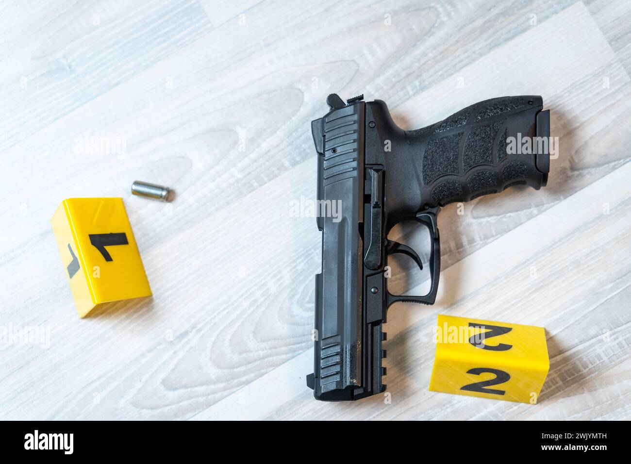 Augsburg, Bavaria, Germany - February 16, 2024: Symbolic image crime scene after a shooting spree staged scene. Pistol with shell casings scattered on the ground with police evidence markings *** Symbolbild Tatort nach einer Schießerrei gestellte Szene. Pistole mit Patronenhüsel auf dem Boden verteilt mit Beweismittel Markierungen der Polzei Stock Photo