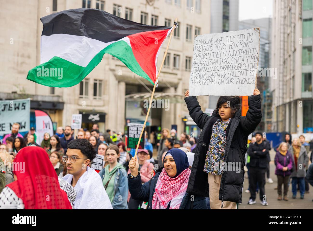 Leeds, UK. 17 FEB, 2024. A young child at the pro palestine protest in Leeds city square holds a sign with a list of countries that crimes against children are alleged to have been commited in. Credit Milo Chandler/Alamy Live News Stock Photo