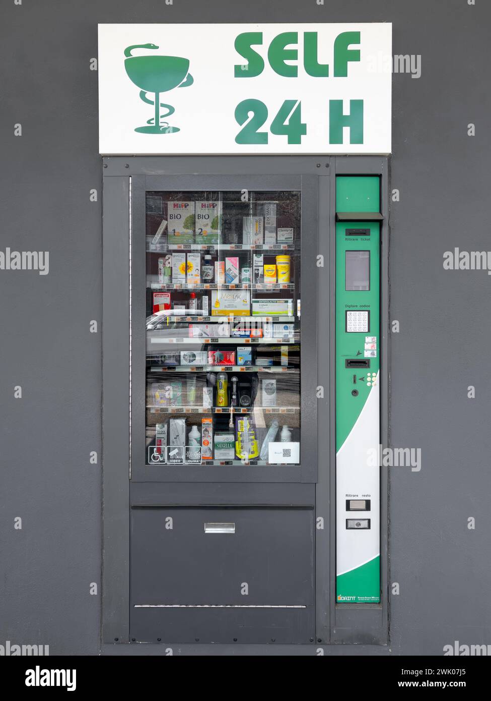 Italy - February 17, 2024: Self 24-hour vending machine for pharmaceuticals and condoms on gray wall and with green logo sign Stock Photo