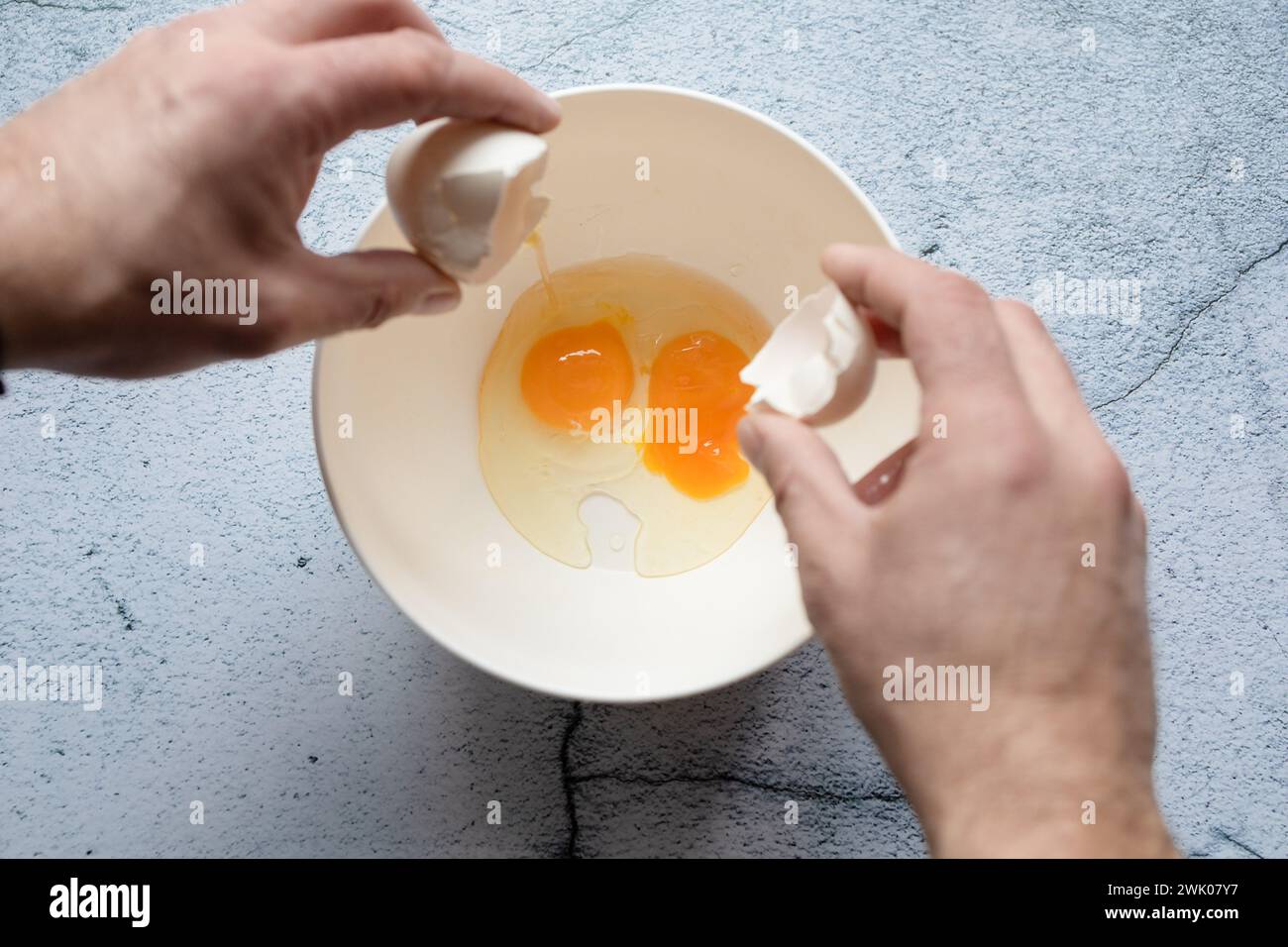 Hands cracking an egg with two yolks inside Stock Photo Alamy