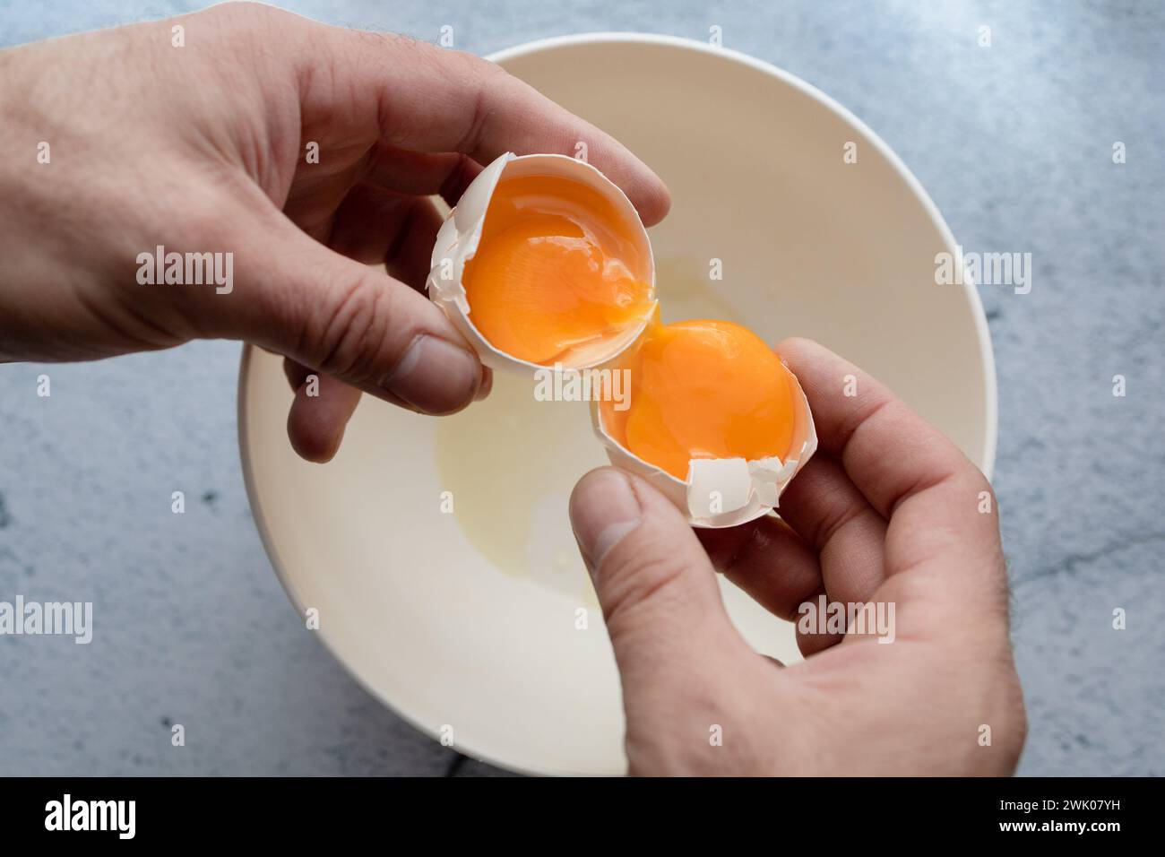 Hands cracking an egg with two yolks inside Stock Photo Alamy