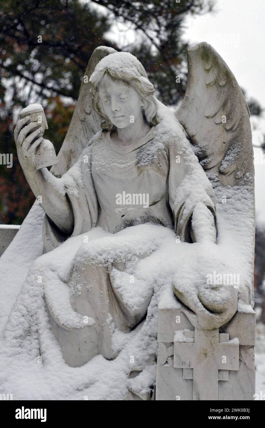 Snow-covered sculpture of an angel at a grave in Montreal's Notre-Dame-des-Neiges Cemetery. Stock Photo