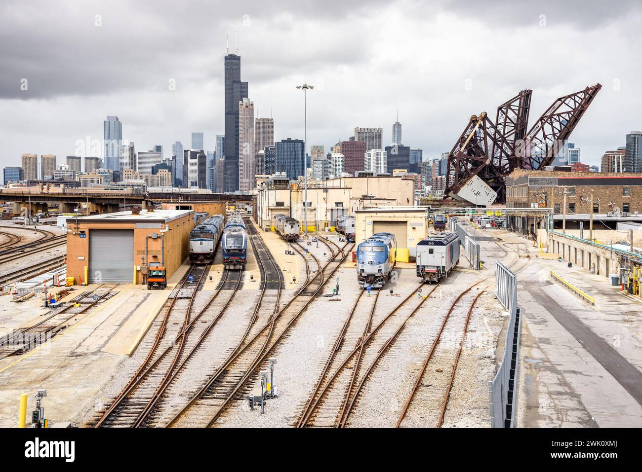 Diesel locomotives at a suburban train depot on a cloudy day. Downtown Chicago Skyline and an open draw bridge are in background Stock Photo