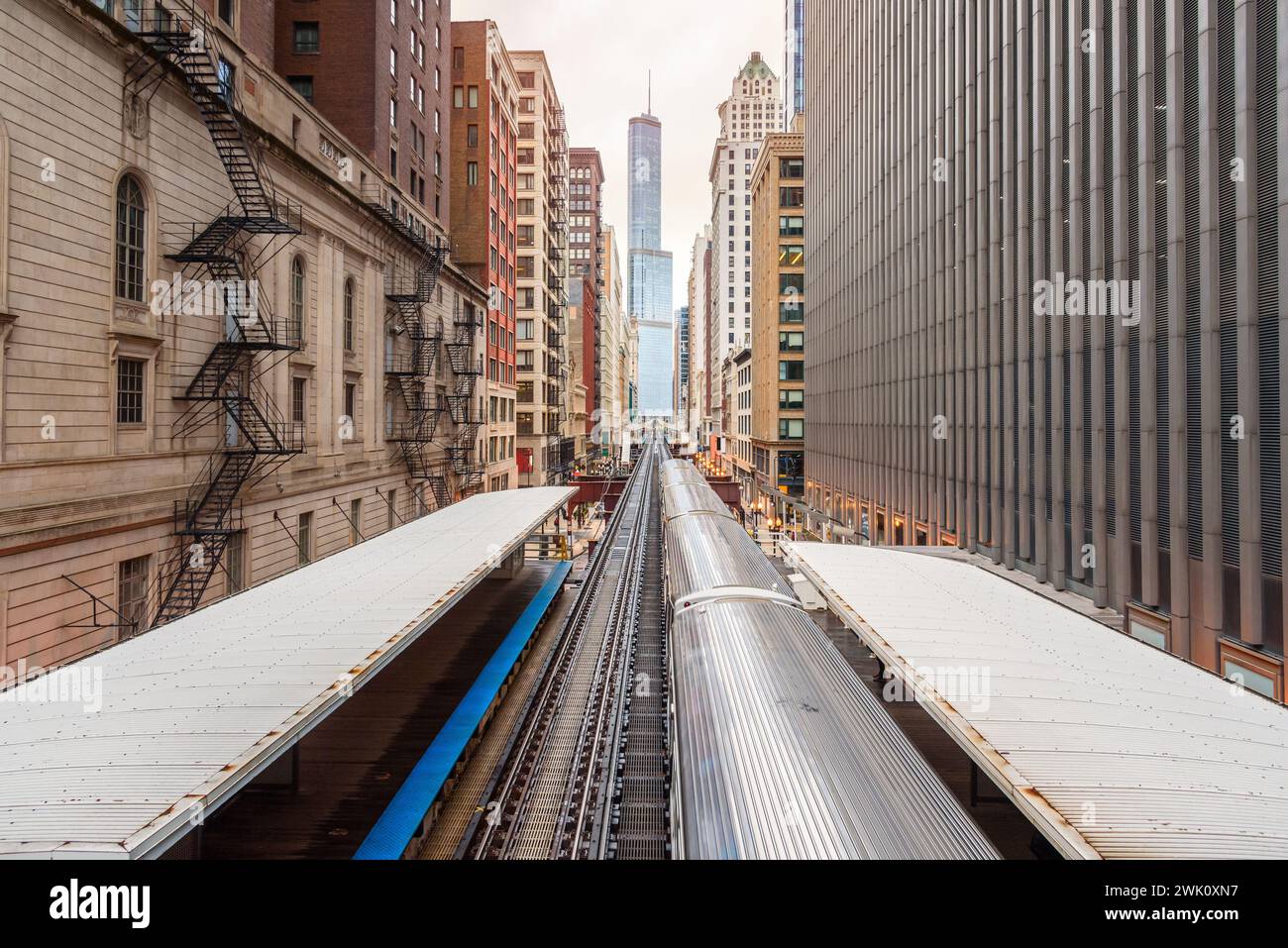 Silver light train pulling away from an elevated station in downtown Chicago on a cloudy spring day Stock Photo