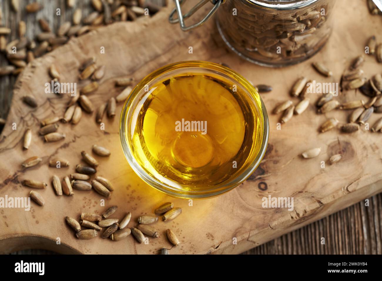 Milk thistle oil in a bowl with Carduus marianus seeds on a table Stock Photo