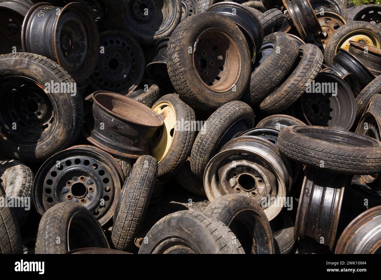 Pile of assorted discarded car and truck tires and steel rims at scrap