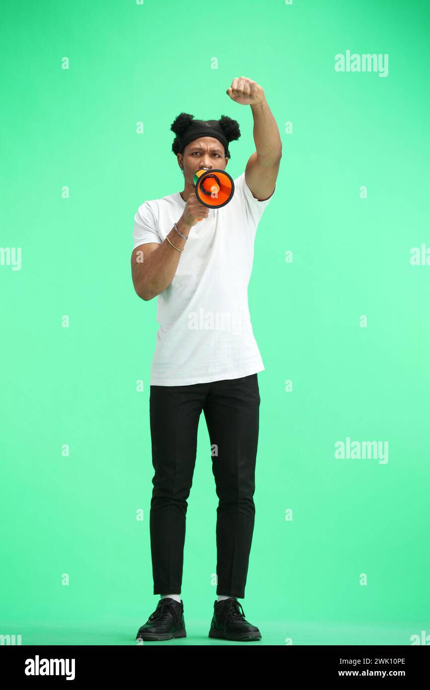 A man, full-length, on a green background, with a megaphone Stock Photo
