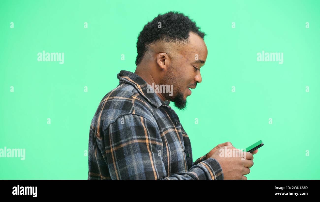 Man, close-up, on a green background, using a phone Stock Photo
