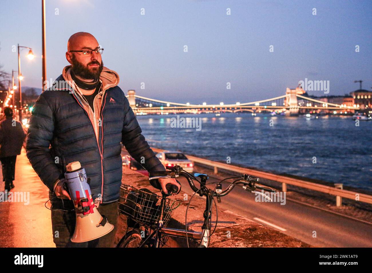 Budapest, Budapest, Hungary. 17th Feb, 2024. Hungarian activist, Balasz T., holds a bull horn with the chain bridge in back ground along the Danube after a speech where Hungarian Prime Minister VIKTOR ORBAN made his annual speech and comments on three resignations of Hungarian President, KATALIN NOVAK; former Minister and leadership of Hungarian Reform Church, ZOLTAN BALOG and former Justice Minister, JUDIT VARGA following exposure of a man pardoned last year from covering up pedophilia in a children's home. The reveal has caused embarrassment and tarnished the image of Hungary's safe z Stock Photo