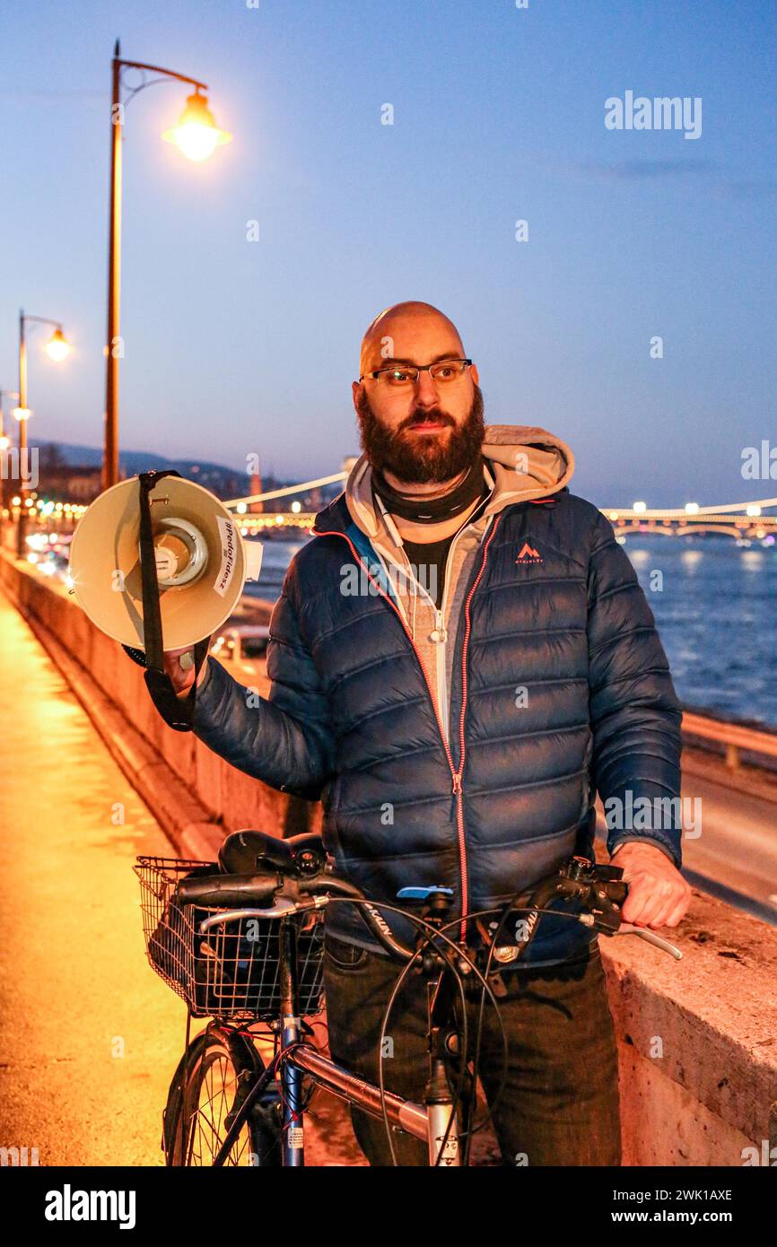 Budapest, Budapest, Hungary. 17th Feb, 2024. Hungarian activist, Balasz T., holds a bull horn with the chain bridge in back ground along the Danube after a speech where Hungarian Prime Minister VIKTOR ORBAN made his annual speech and comments on three resignations of Hungarian President, KATALIN NOVAK; former Minister and leadership of Hungarian Reform Church, ZOLTAN BALOG and former Justice Minister, JUDIT VARGA following exposure of a man pardoned last year from covering up pedophilia in a children's home. The reveal has caused embarrassment and tarnished the image of Hungary's safe z Stock Photo