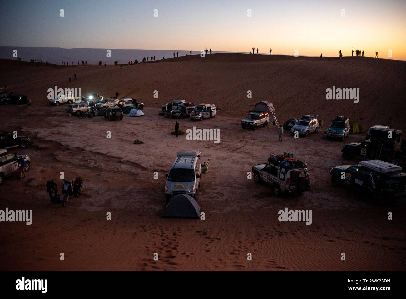 Racers Are Looking At The Sunrise From A Dune At The Sahara Desert In racers-are-looking-at-the-sunrise-from-a-dune-at-the-sahara-desert-in