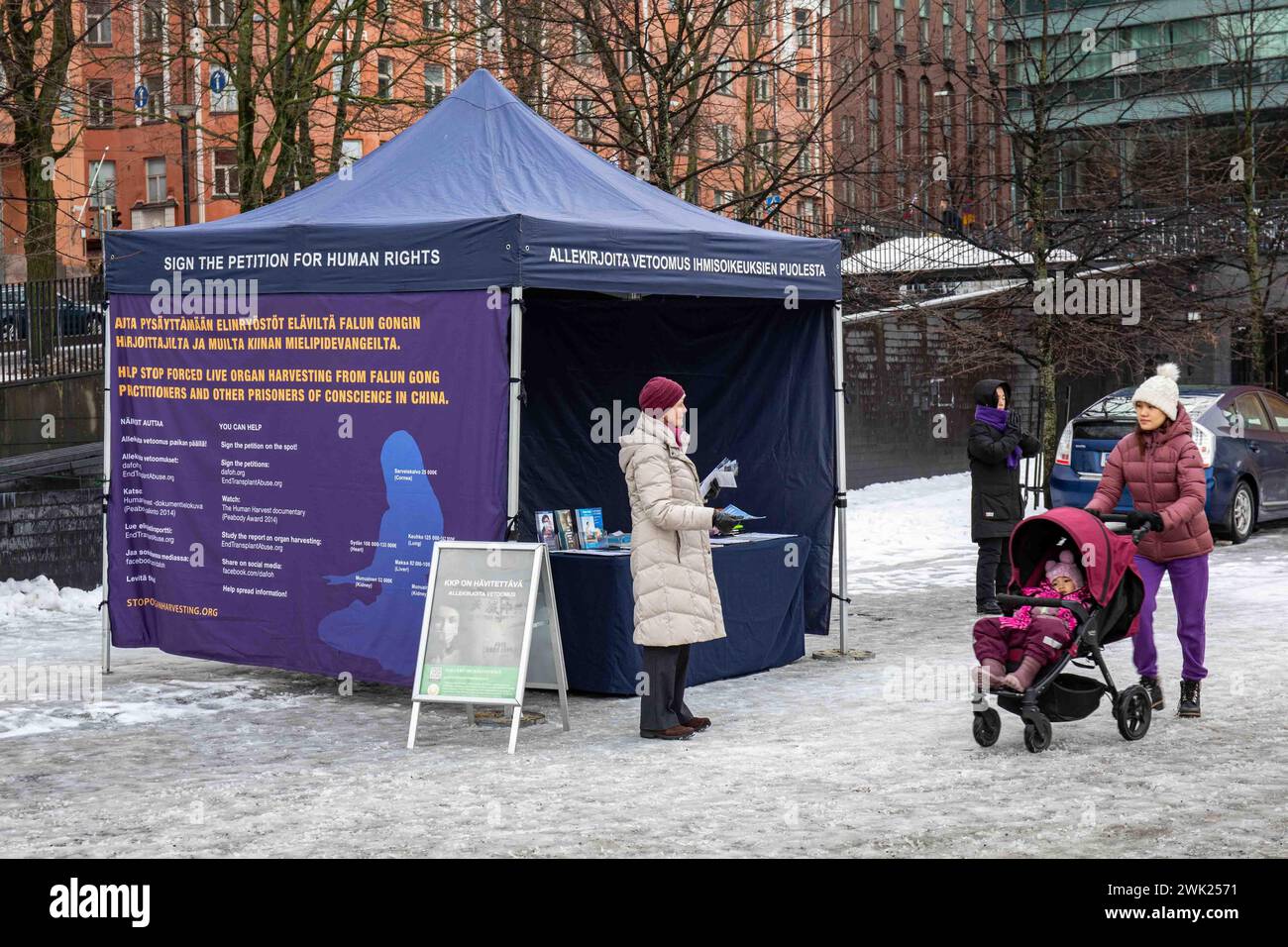 Falun Gong or Falun Dafa flyer distributor offering leaflets to passersby in front of a marquee or tent in Kamppi district of Helsinki, Finland Stock Photo