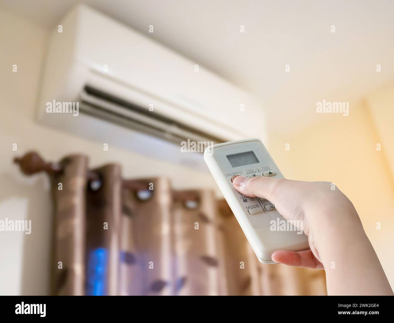 Hand hold remote control directed on the air conditioner Stock Photo