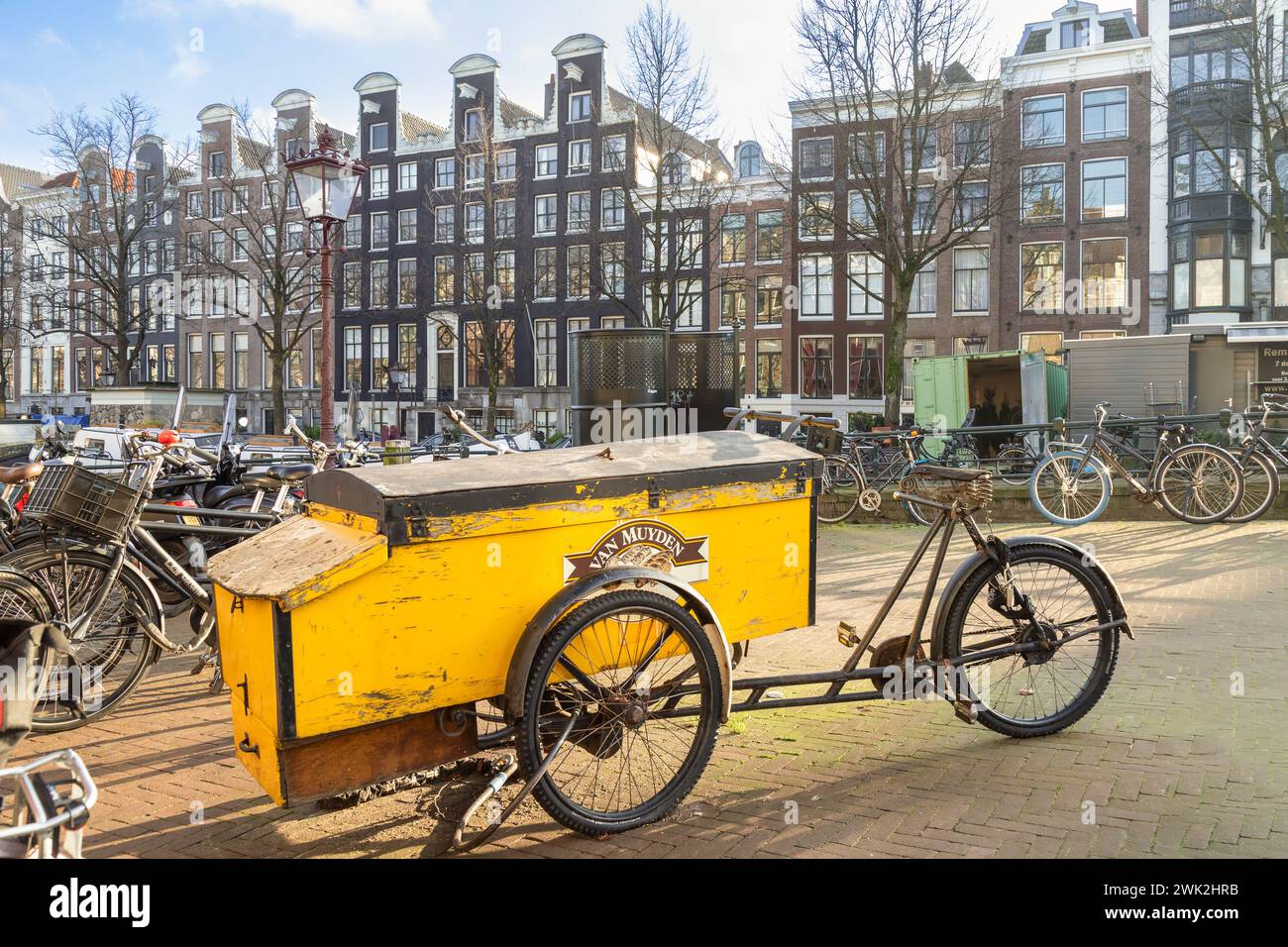Old yellow cargo bike along the canal in Amsterdam. Stock Photo