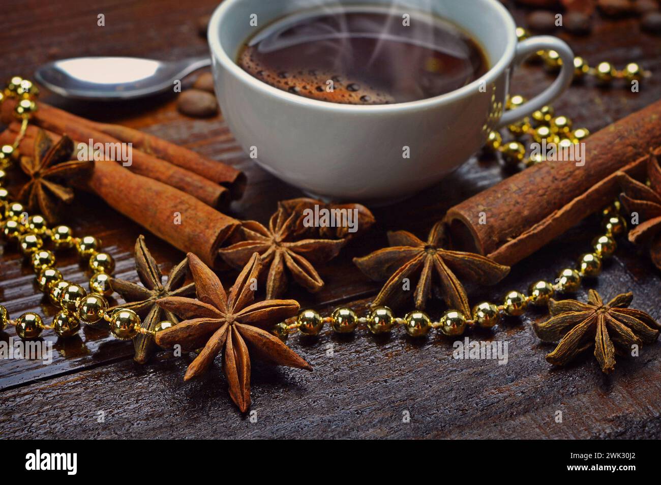A cup of hot coffee, star anise and cinnamon sticks among festive tinsel. Aromas holiday. Home comfort. Christmas atmosphere. Morning.Close-up. Stock Photo