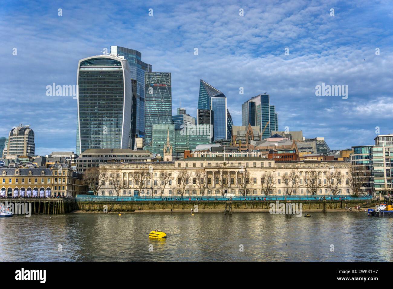 Buildings of the City of London seen across the River Thames, with modern skyscrapers dominating skyline behind the old Billinsgate market building. Stock Photo