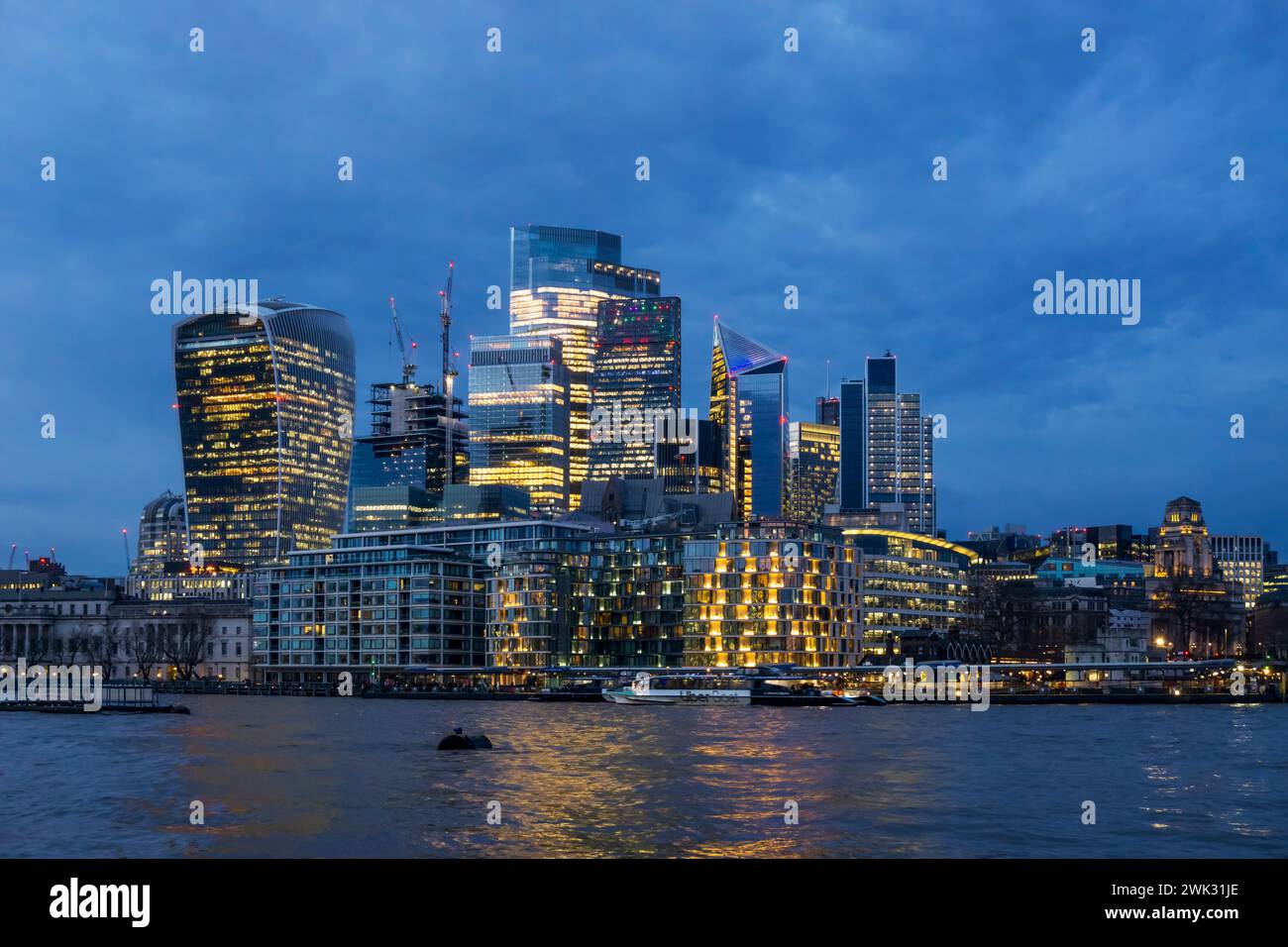 The dense commercial development of the City of London skyline seen across the River Thames at dusk. Stock Photo