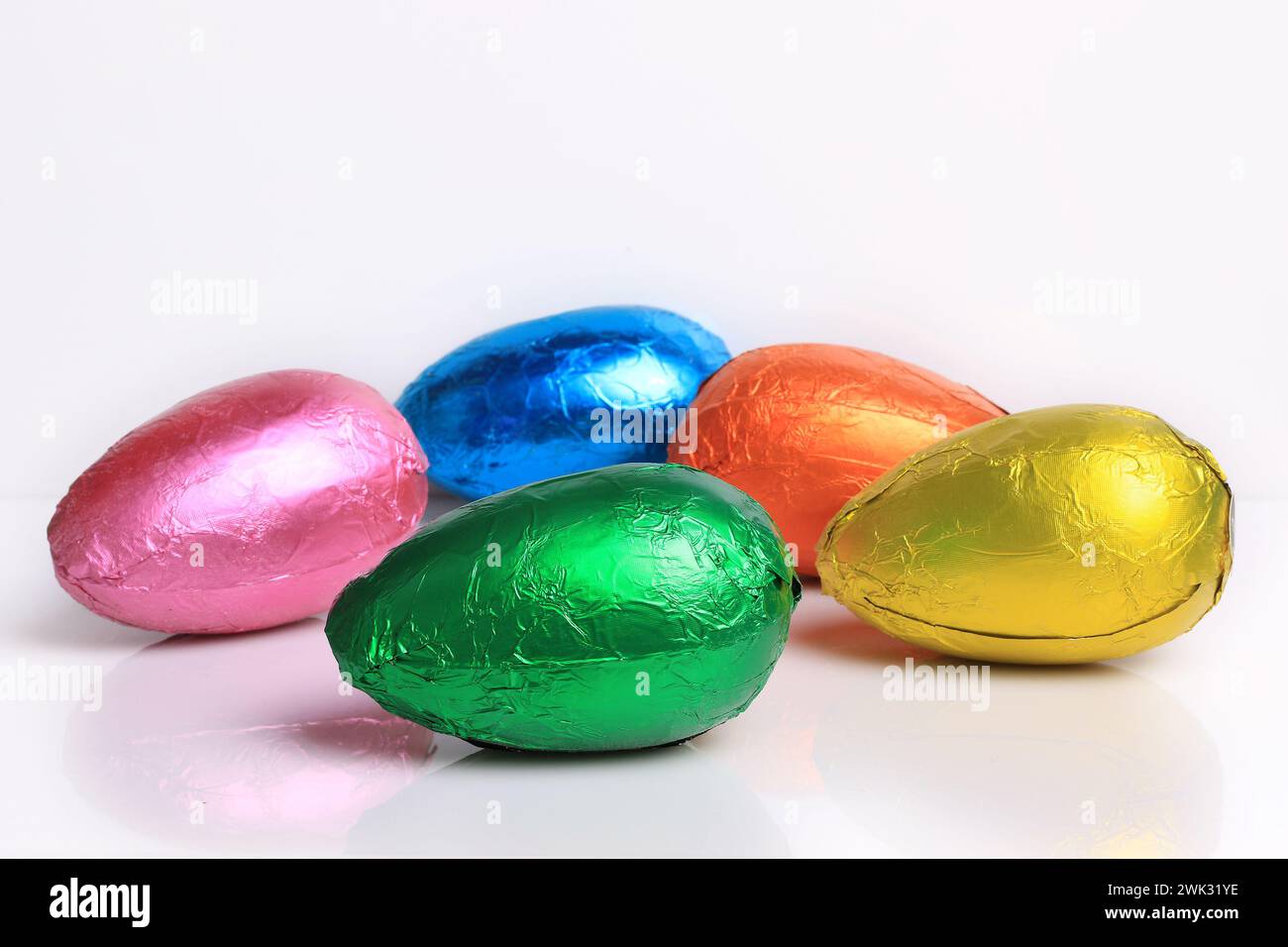 Five brightly colored chocolate Easter eggs on white. Stock Photo