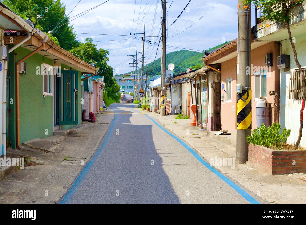 Donghae City, South Korea - July 28th, 2019: A blue-lined bike path meanders through the heart of Mukho Port, flanked by low houses of the fishing com Stock Photo
