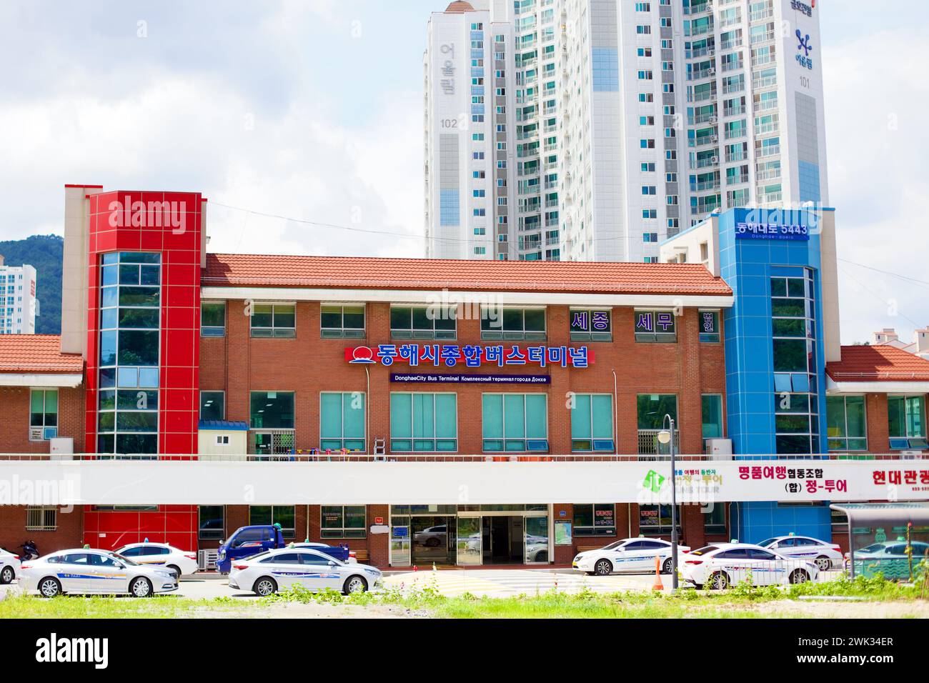 Donghae City, South Korea - July 28th, 2019: The brick facade of Donghae City's Intercity Bus Terminal stands prominently, with a high-rise apartment Stock Photo