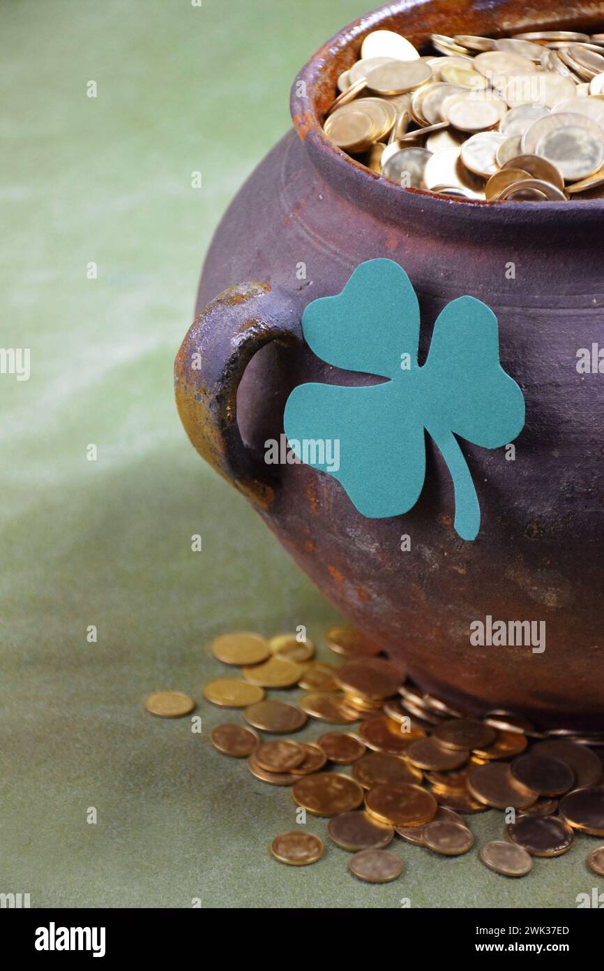 Happy St. Patrick's Day .A pot full of gold coins and shamrock leaf.Luck of the Irish: A pot of Gold sits amongst the shamrocks as a symbol of fortune Stock Photo