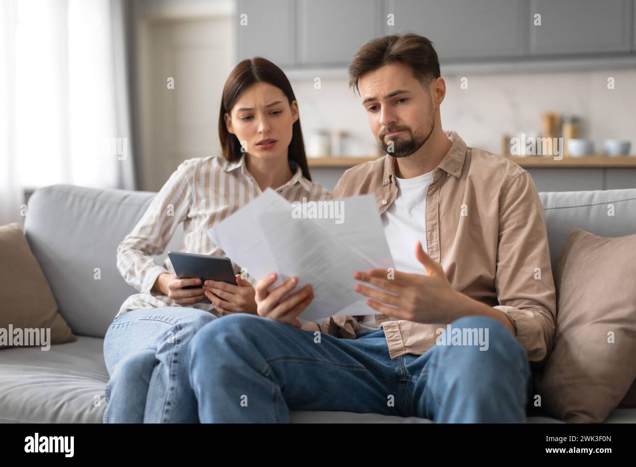Spouses reviewing documents and using tablet at home Stock Photo