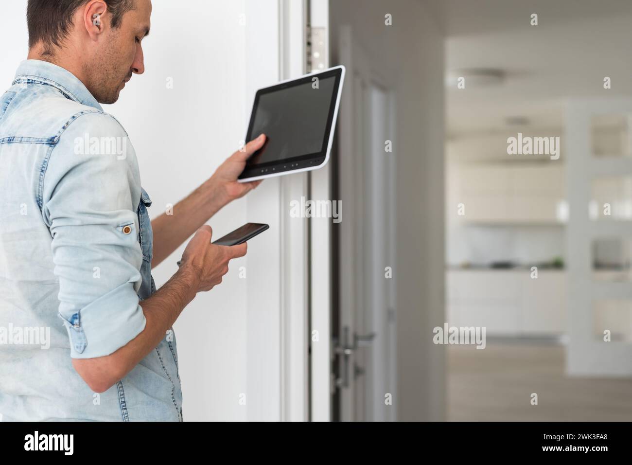 Young electrician installing security alarm on wall Stock Photo