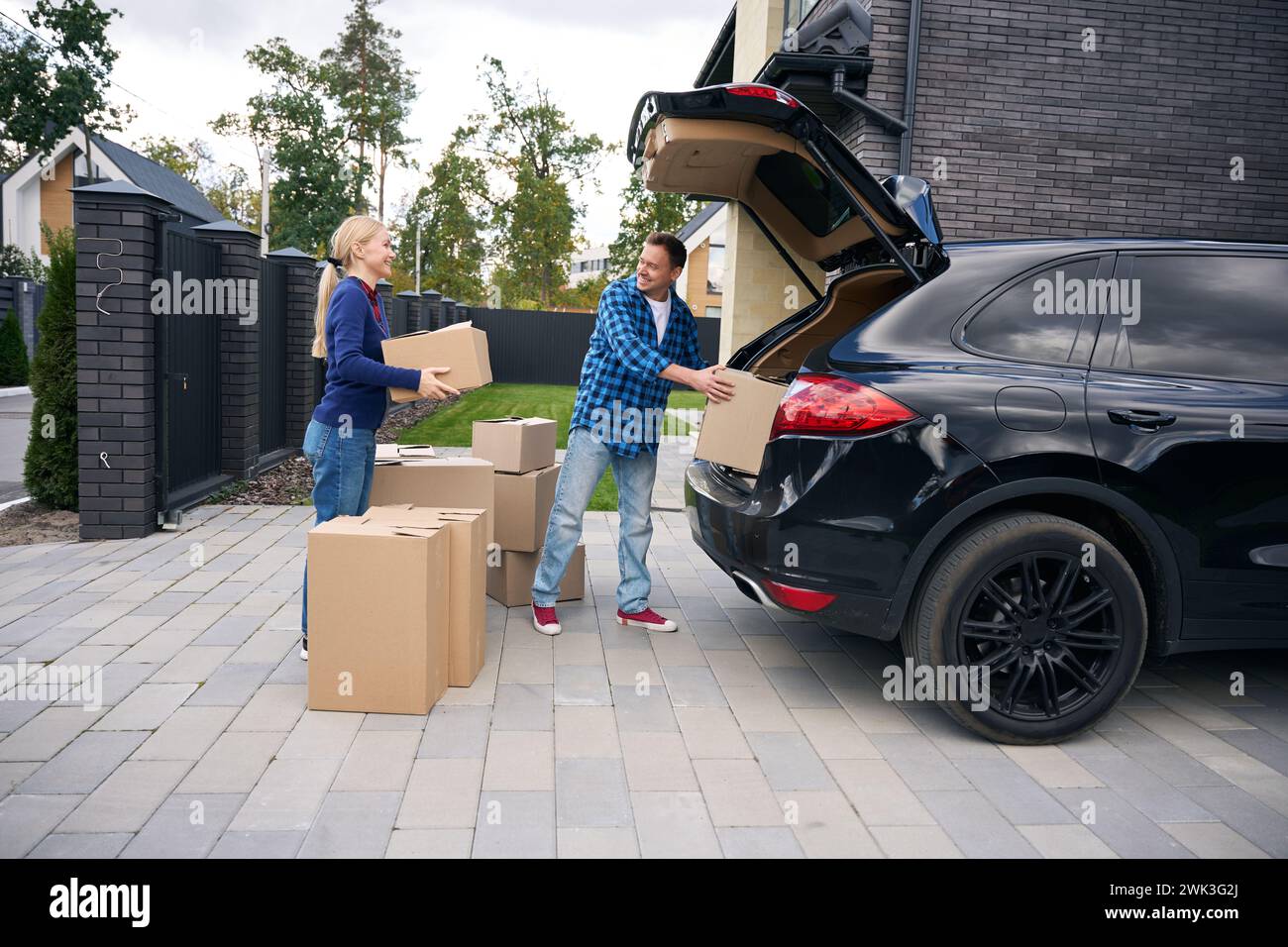 Happy couple standing near car and loading boxes in it Stock Photo